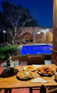 a table with food on it next to a swimming pool at Ouberge 'loassis house in Douar Azrou Melloul