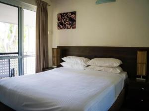 a bedroom with a large white bed with a window at Reef Resort Villas Port Douglas in Port Douglas