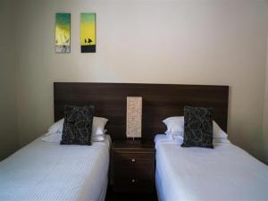 a bedroom with two beds and a nightstand with two beds sidx sidx at Reef Resort Villas Port Douglas in Port Douglas