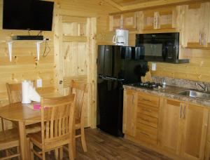 a kitchen with a black refrigerator and a table at Lake Minden Camping Resort Cottage 2 in Nicolaus