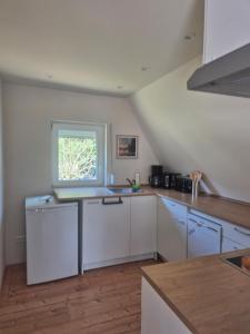 a kitchen with white cabinets and a window at Ferienhaus am Helenesee 17 in Frankfurt Oder +2 photos