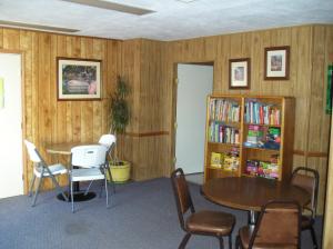 a room with a table and chairs and a book shelf at Lake Minden Camping Resort Cabin 1 in Nicolaus