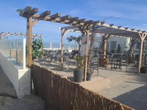 eine hölzerne Pergola mit Tischen und Stühlen am Strand in der Unterkunft Lolasurmer in Bredene + 11 Fotos