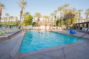 una piscina con sillas y palmeras en Palm Springs Camping Resort Loft Cabin 1, en Palm Desert