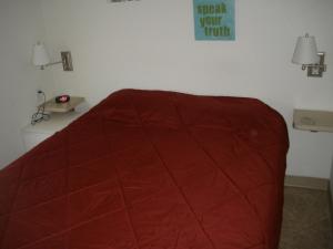 a bed with a red comforter in a room at Palm Springs Camping Resort Cottage 1 in Palm Desert