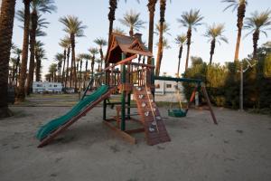 a playground with a slide in the sand with palm trees at Palm Springs Camping Resort Cottage 1 in Palm Desert