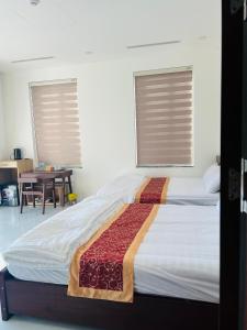 a bed in a bedroom with two windows and a table at Green Hotel in Khánh Dương