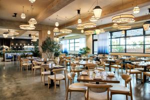 a restaurant with wooden tables and chairs and windows at The Shay, a Destination by Hyatt in Los Angeles