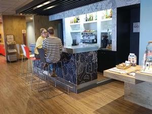 two people sitting at a counter in a store at ibis Aurillac in Aurillac