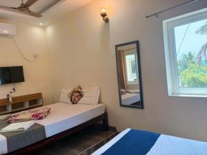 a bedroom with a bed and a mirror and a window at Serenity Beach House in Pondicherry