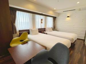 a hotel room with two beds and a yellow chair at BREATH HOTEL in Fujisawa