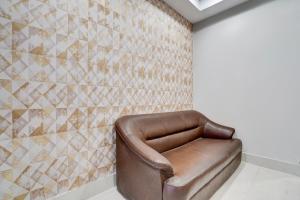 a leather chair in a room with a tiled wall at Super Collection O AIIMS Bhubaneshwar in Khandagiri