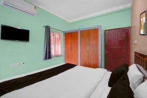 a bedroom with a white bed and a tv at Townhouse Loknath Temple Road Puri Formerly Rashmi Villa in Puri +27 photos