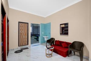 a living room with a red couch and two chairs at Townhouse Loknath Temple Road Puri Formerly Rashmi Villa in Puri