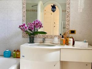 a bathroom with a sink with a mirror and purple flowers at Syrene Suites Sorrento in Piano di Sorrento +80 photos