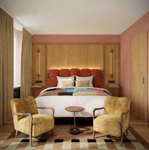 a bedroom with a large bed and two chairs at Hotel Alpina Luzern in Lucerne