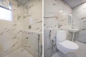 a white bathroom with a toilet and a sink at FabHotel Kences Inn in Chennai +22 photos