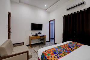 a bedroom with a bed and a chair and a tv at FabHotel Kences Inn in Chennai