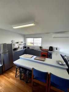 a kitchen with a table and some chairs and a refrigerator at Saturn Parade Shack in Venus Bay