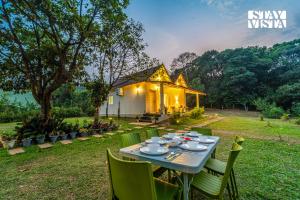 a table and chairs in front of a house at StayVista at Jungle Jade with WiFi in Madikeri