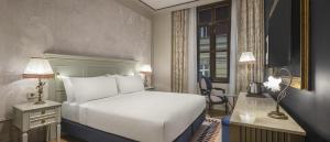 a hotel room with a white bed and a desk and a window at Palazzo Donizetti Istanbul, Tapestry Collection by Hilton in Istanbul