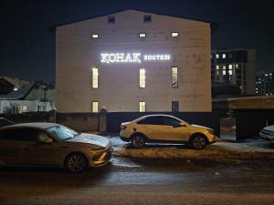 two cars parked in a parking lot in front of a building at Qonaq Hostel in Astana