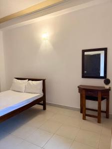 a room with a bed and a tv and a table at Hillcrest Bungalow in Matale