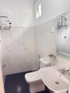 a white bathroom with a toilet and a sink at Hillcrest Bungalow in Matale