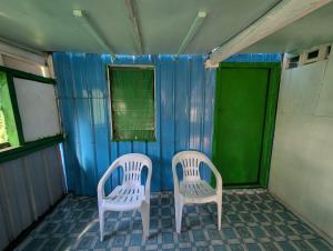 two white chairs sitting in a room with blue walls at Lamkail beach island bungalow in Lénakel