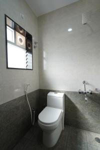 a bathroom with a white toilet and a window at Golden Comforts Banglore in Bangalore +3 photos