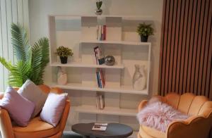 a living room with two chairs and shelves with books at Nuit au Ranch Horse Paradise & Jacuzzi in Boutigny-sur-Essonnes