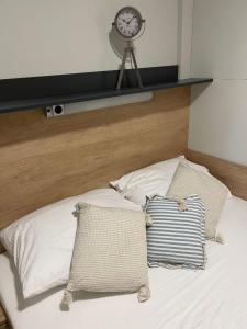 a bed with two pillows and a clock on the wall at Mobile Home River in Privlaka