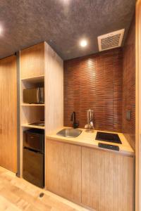 a kitchen with wooden cabinets and a sink and a stove at 鴨川せせらぎ庵 in Kyoto