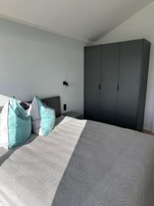 a bedroom with a large bed with two blue pillows at Ferienhaus Sonnenperle am Partwitzer See in Klein Partwitz