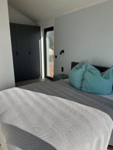 a bedroom with a large bed with blue pillows at Ferienhaus Sonnenperle am Partwitzer See in Klein Partwitz +9 photos