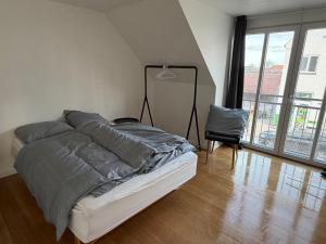 a bedroom with a bed with gray sheets and a chair at Kystvejen Øster Hurup in Hadsund