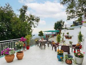 a patio with tables and chairs and potted plants at Oliva by Quercus Oak Stays in Mussoorie