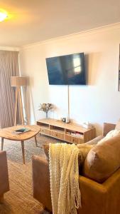 a living room with a couch and a flat screen tv at Blue Waters - Beachfront and River View - Sleeps 6 -Central Kalbarri in Kalbarri
