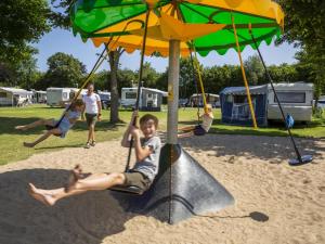a young boy is sitting on a swing under an umbrella at DCU-Camping Odense in Odense