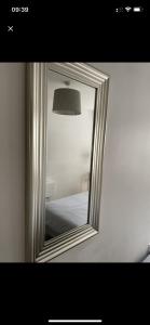 a mirror hanging on a white wall with a lamp at Oakwood in Fleet