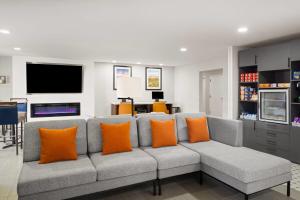 a living room with a gray couch with orange pillows at Wingate by Wyndham Los Alamos in Los Alamos