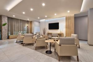 a waiting room with tables and chairs and a tv at Wyndham Garden Anna in Anna