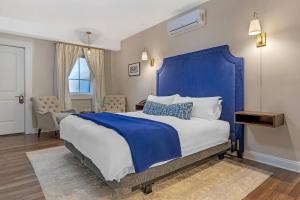 a bedroom with a large bed with a blue headboard at The Colonial Inn, an Ascend Collection Hotel in Hillsborough
