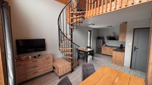 a living room with a spiral staircase and a kitchen at Domki u Ralfiego in Łuka
