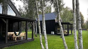 a black house with a picnic table and some trees at Domki u Ralfiego in Łuka