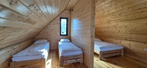 two twin beds in a wooden cabin at Domki u Ralfiego in Łuka