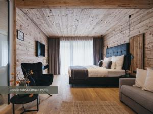a bedroom with a bed and a chair and a couch at VAYA Post Montafon - Neueröffnung Dezember 2026 in Gaschurn +17 photos