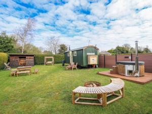 a yard with benches and a camping trailer at Twit Twoo Shepherds Hut in Louth