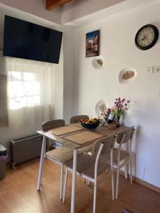 a dining room table with chairs and a clock on the wall at Tsitsinos maisonette house in Zekros