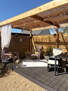 a patio with a wooden pergola with chairs and a table at Maison Chez Marguerite in Saumur